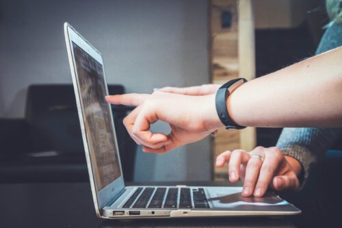 An image of a man pointing at a laptop screen.