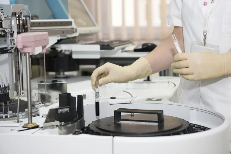 An image of a nurse loading blood samples in a machine.