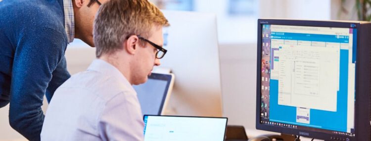 An image of two employees using a computer.