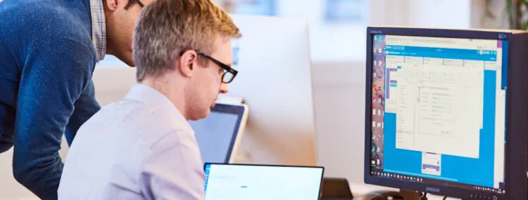 An image of two employees using a computer.