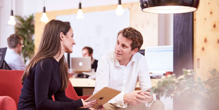 An image of two red c employees talking to each other, one a female and one a male.