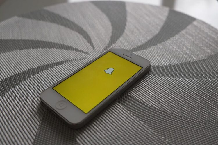 A iPhone 5s displaying the snapchat logo.