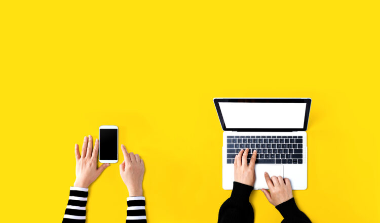 two people working together. One on a phone the other on a laptop.