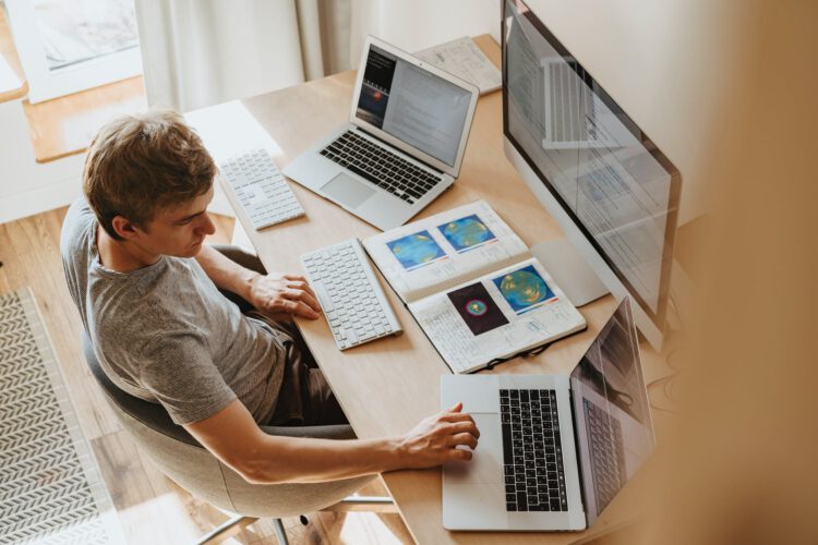 image of a man working with two laptops and one iMac.