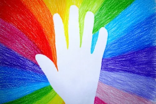 A drawing of a white hand with all colours of the rainbow around in it.