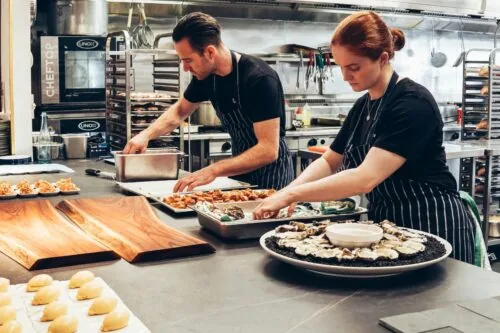 An image of two chefs cooking in a kitchen.